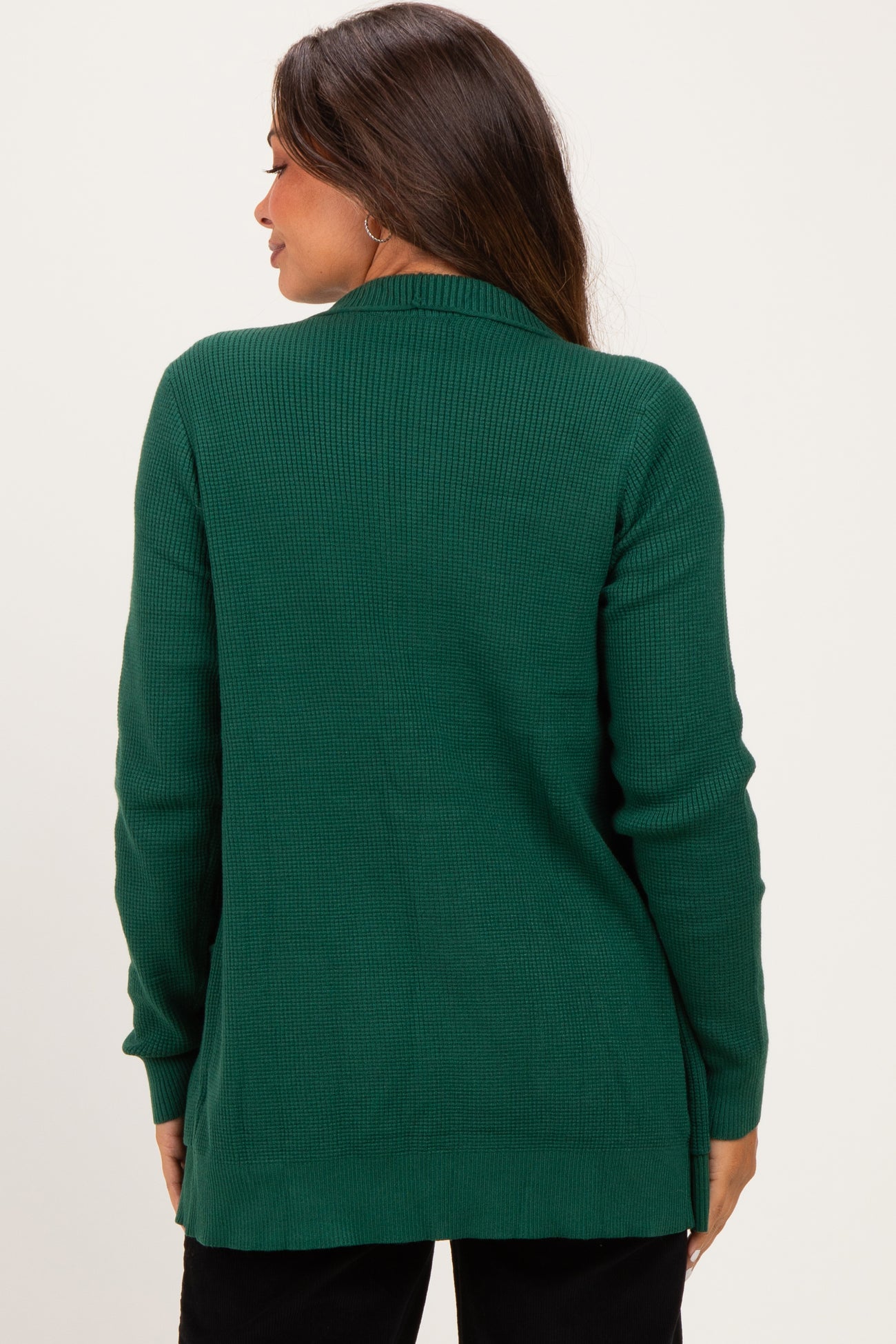 woman wearing a dark green ribbed maternity cardigan, shown from the back, with a relaxed fit and long sleeves