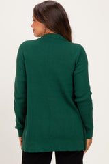 woman wearing a dark green ribbed maternity cardigan, shown from the back, with a relaxed fit and long sleeves