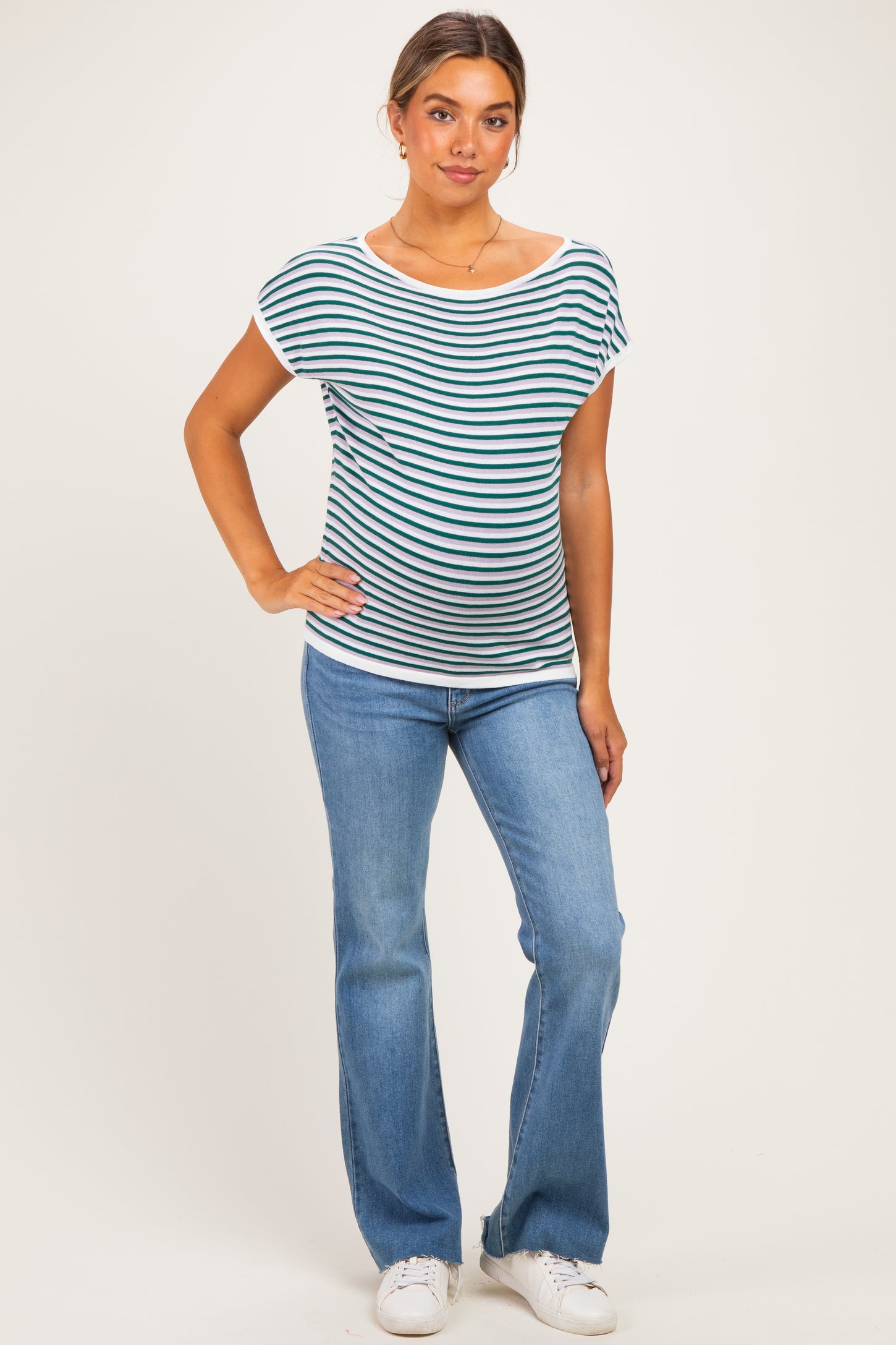 woman wearing a striped maternity top with a relaxed fit and blue flared jeans, showing a baby bump