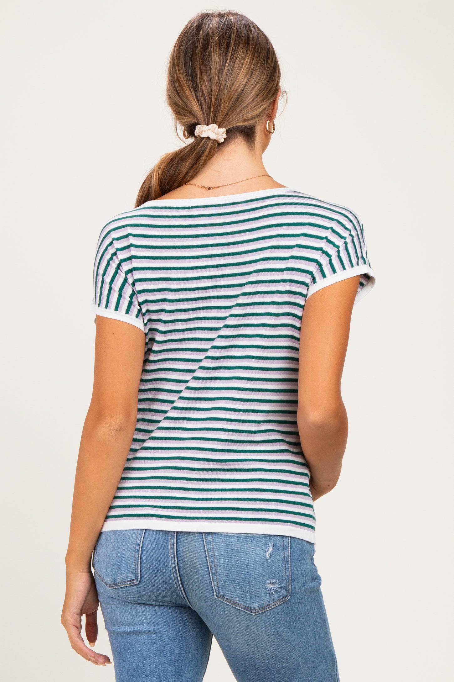 woman wearing a striped maternity top with short sleeves, shown from the back, paired with blue jeans