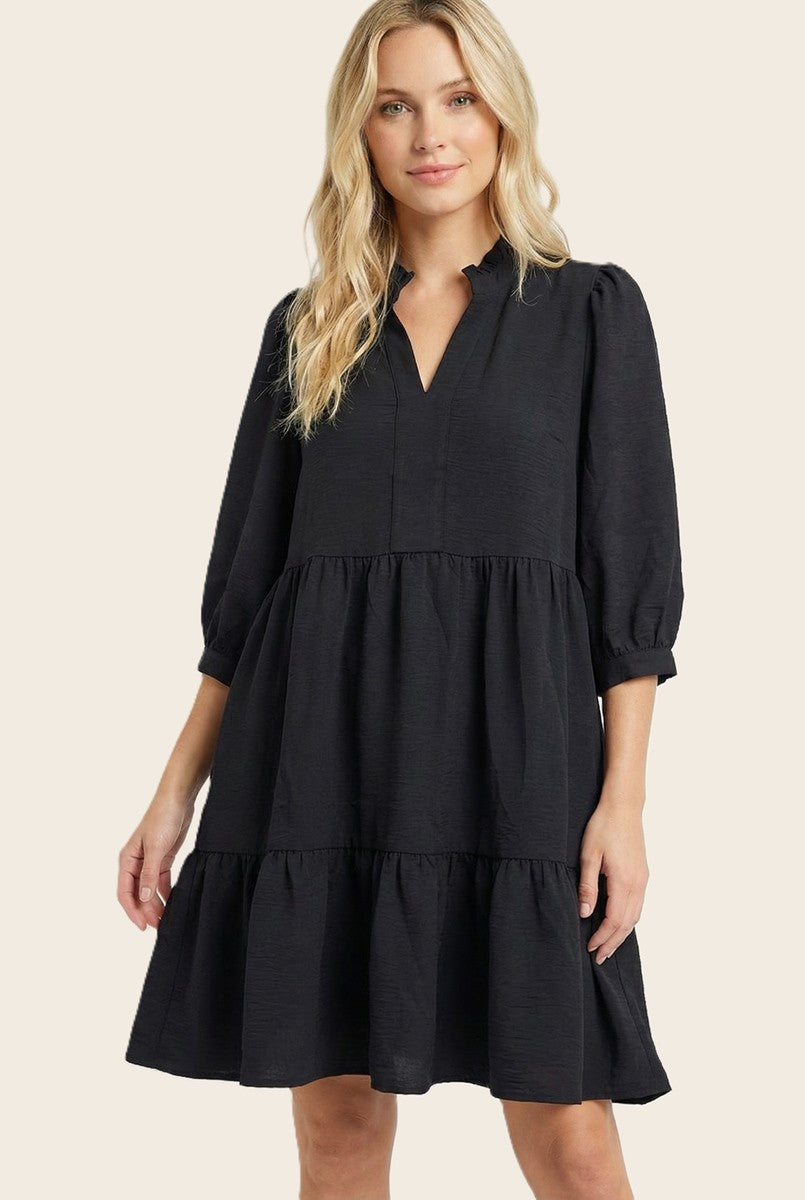 woman wearing a black tiered short sleeve dress with a v-neck and puffed sleeves
