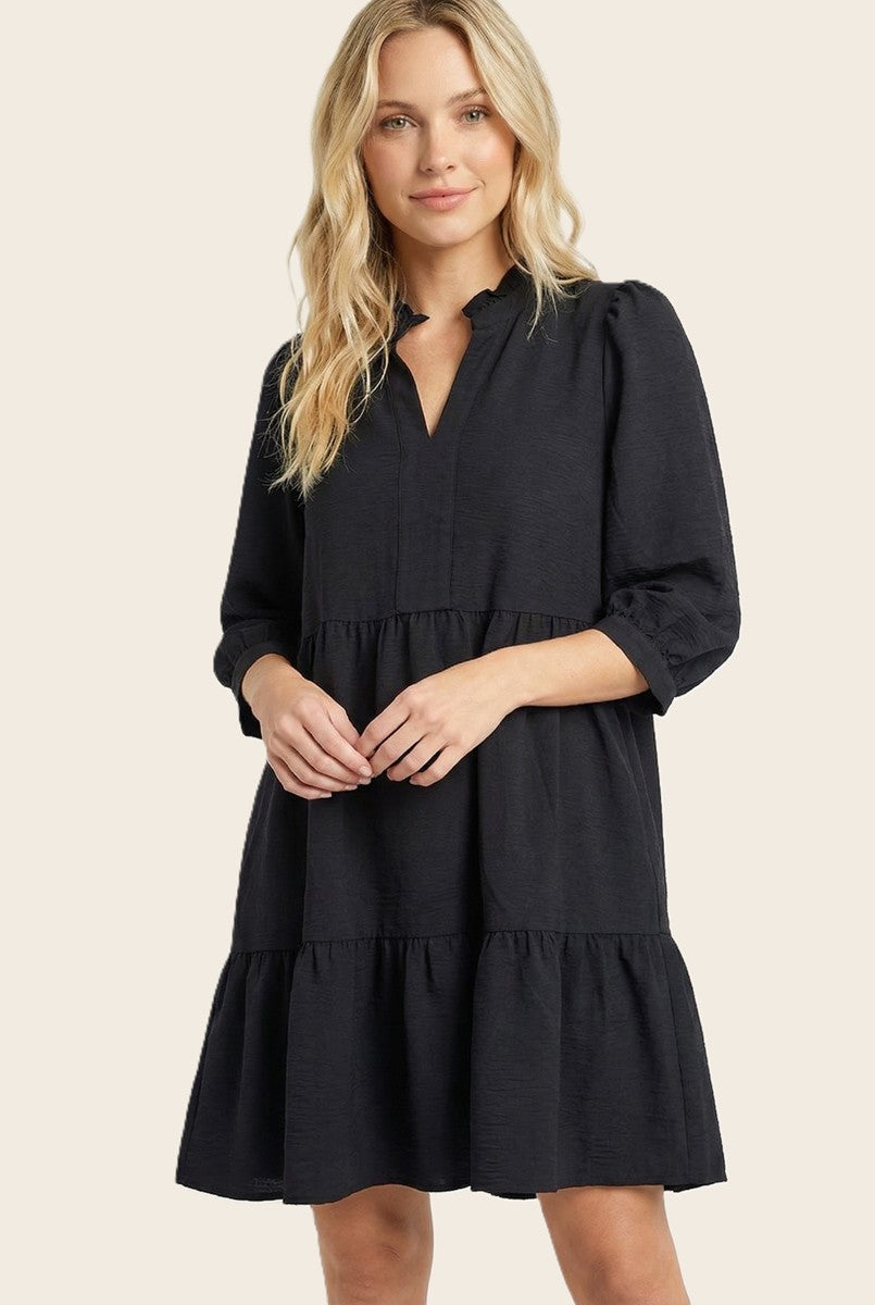 woman wearing a black tiered mini dress with a collar and three-quarter puff sleeves