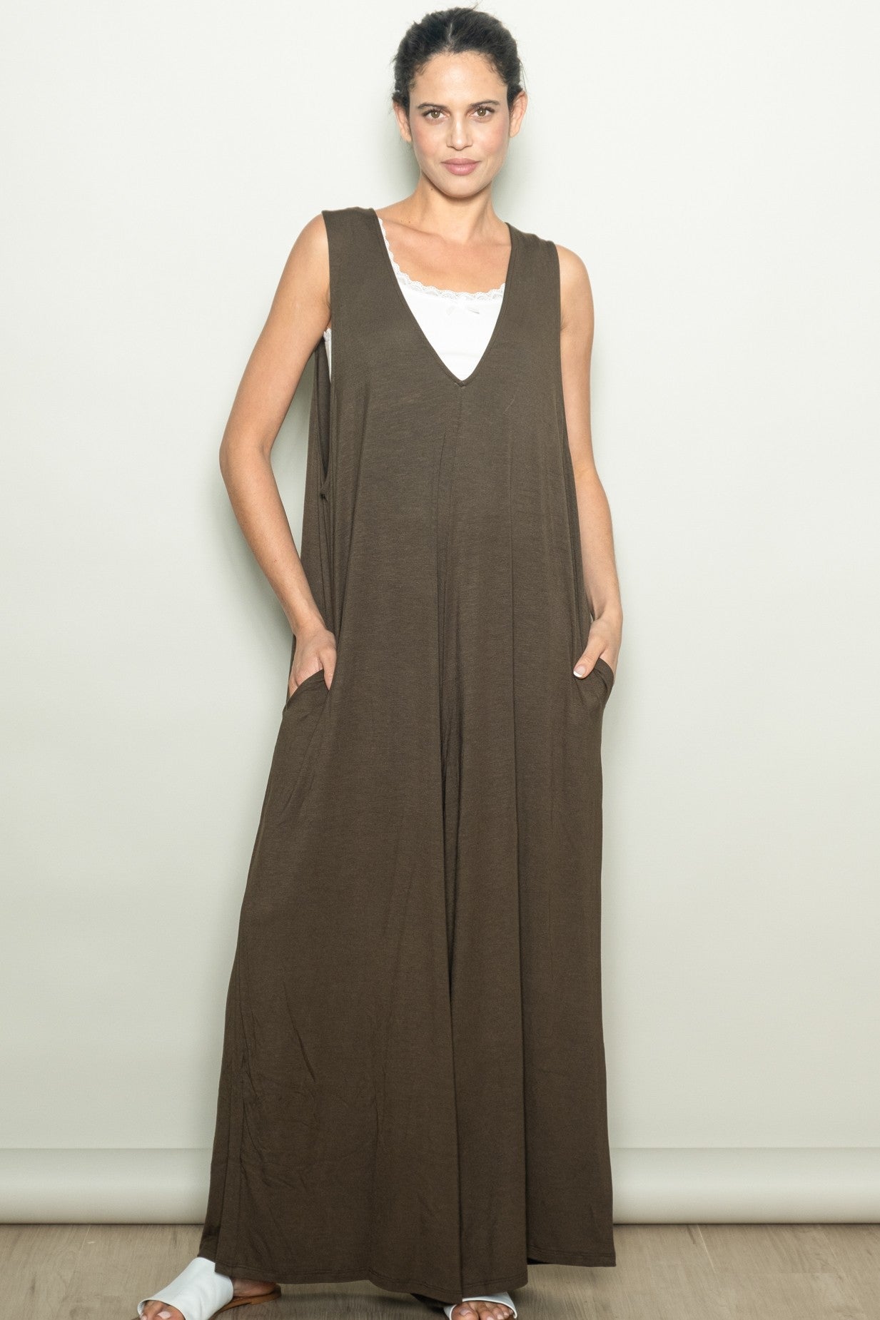 woman wearing a brown sleeveless maxi dress with side pockets and a v-neckline