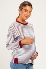 woman wearing a red and white striped maternity top and holding her baby bump