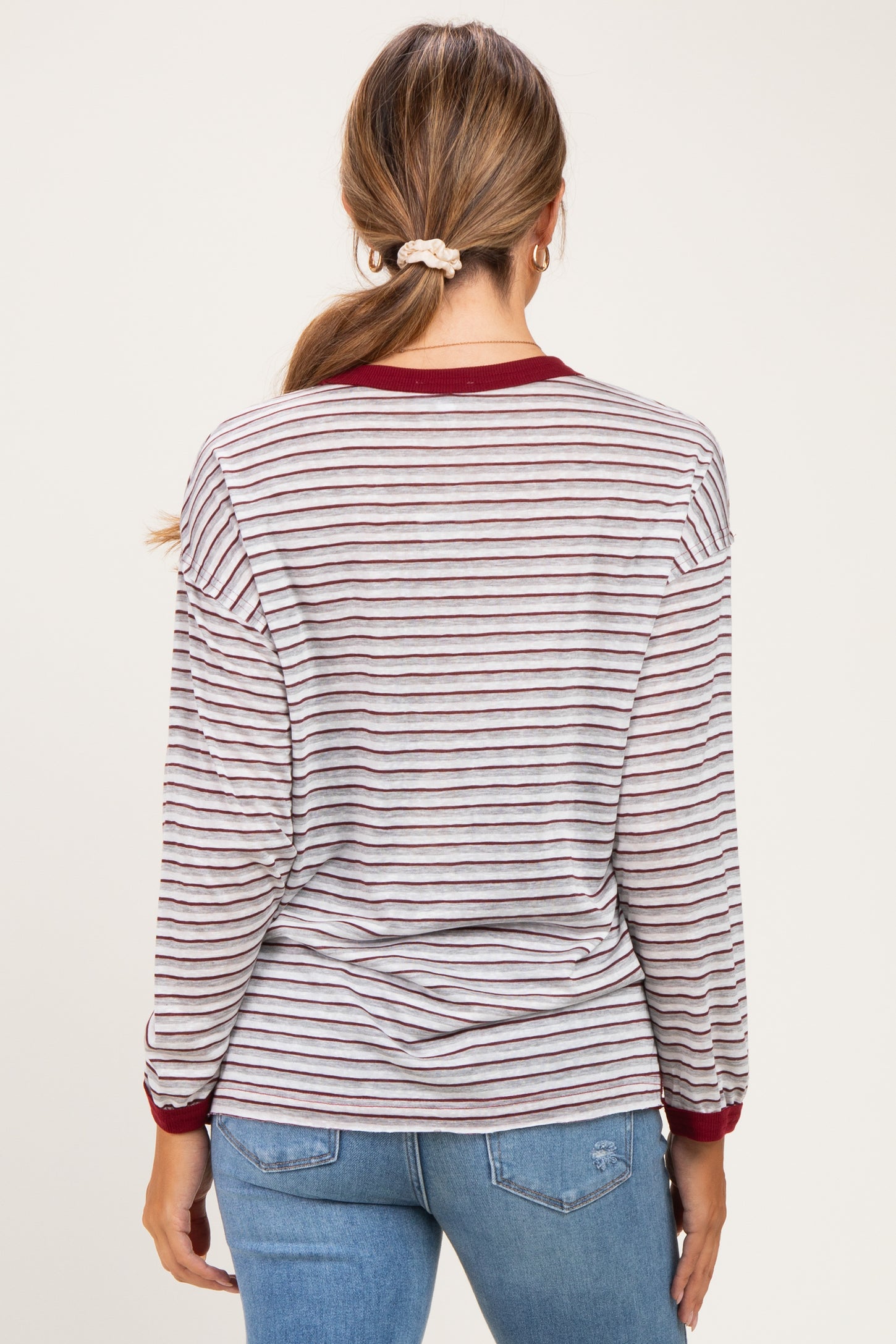 woman wearing a striped long sleeve maternity top with maroon accents and a round neckline, showing her back
