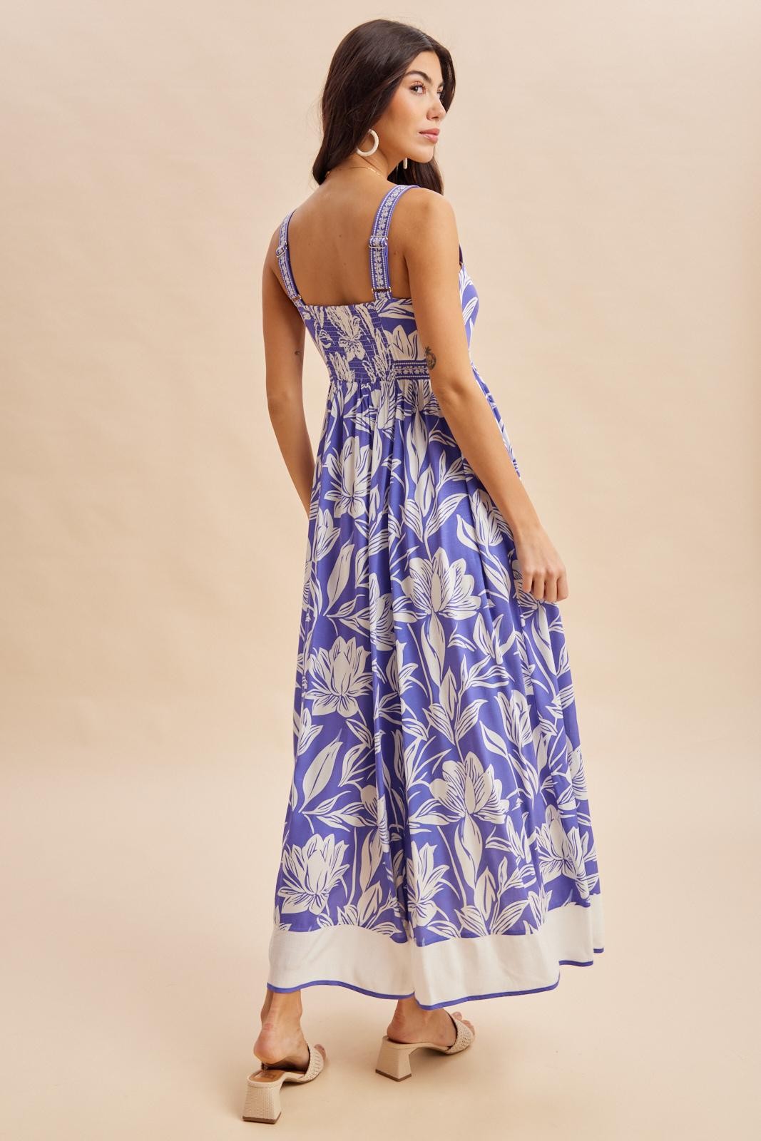 woman wearing a floral blue maxi dress with a square back and smocked bodice facing away from the camera