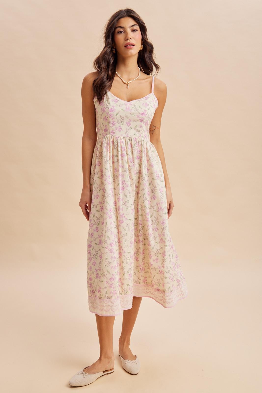 woman wearing a light pink floral midi dress with spaghetti straps and a fitted bodice