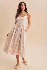 woman wearing a floral patterned midi dress with thin straps and pockets