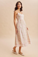 woman wearing a floral print midi dress with thin straps and a flowy skirt