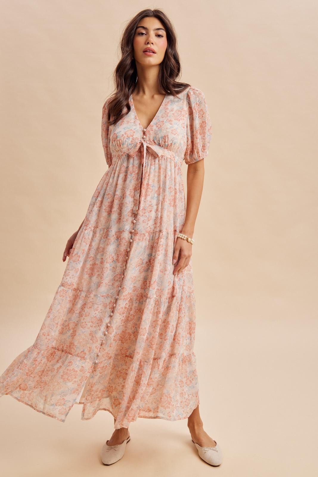 woman wearing a floral maxi dress with puff sleeves and a tie front detail