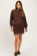 woman wearing a brown maternity sweater dress with striped collar and cuffs, showing a baby bump