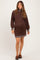 woman wearing a brown maternity sweater dress with striped collar and cuffs, showing a baby bump
