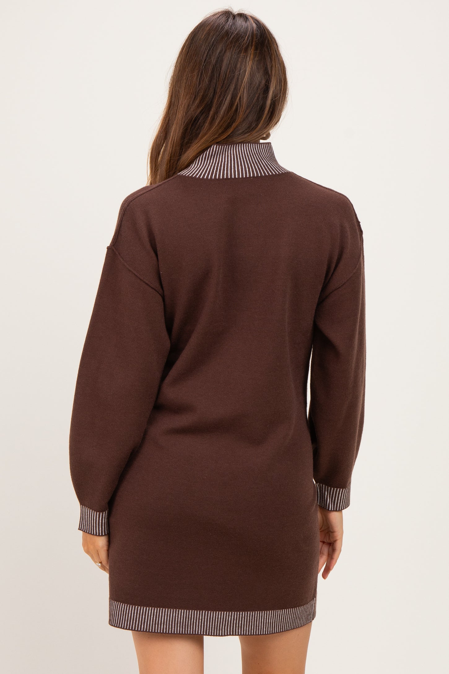 woman wearing a brown maternity sweater dress with a striped collar and cuffs, shown from the back