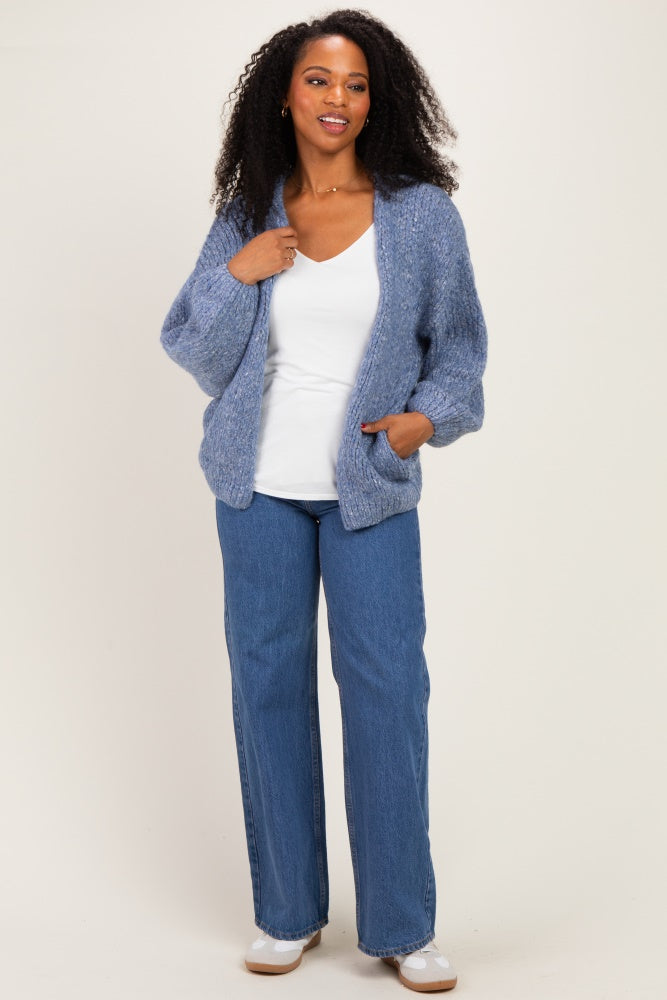 woman wearing a light blue oversized knit cardigan over a white top and blue wide-leg jeans