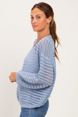 woman wearing a light blue open knit sweater with a relaxed fit and long sleeves, paired with denim jeans