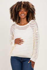 woman wearing a cream lightweight crochet maternity sweater and showing her baby bump