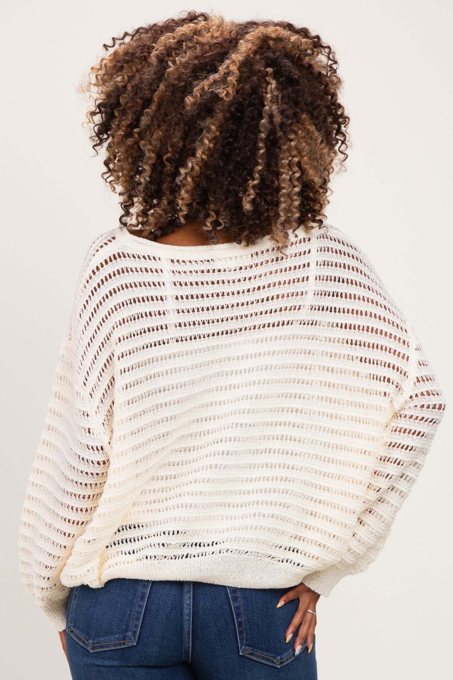 woman wearing a cream open knit maternity sweater with a relaxed fit, seen from the back