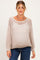 woman wearing a light beige open knit maternity sweater with a visible baby bump and casual jeans
