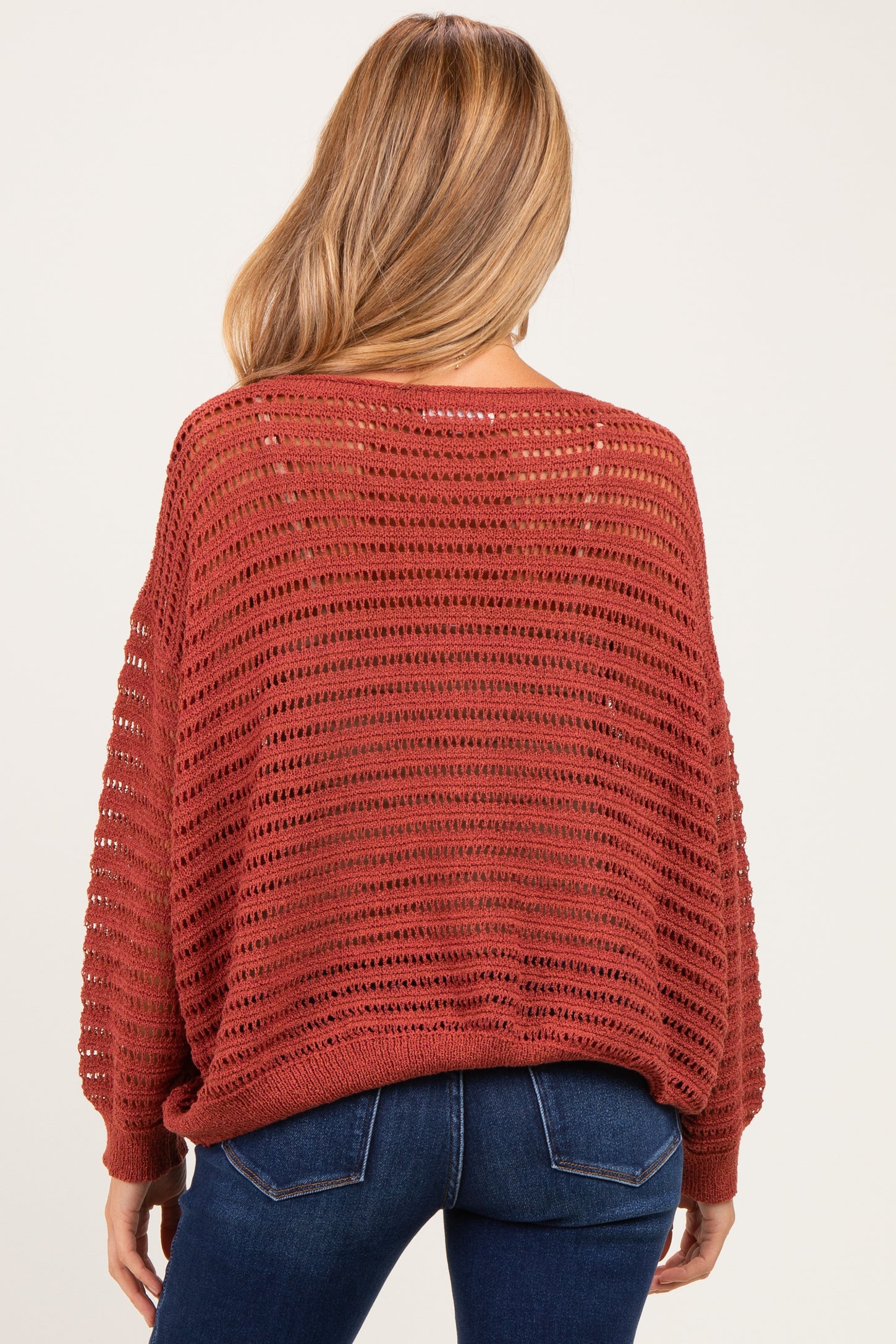 woman wearing a burnt orange open-knit maternity sweater with a relaxed fit and long sleeves