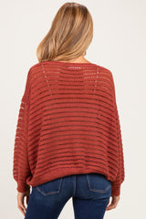 woman wearing a burnt orange open-knit maternity sweater with a relaxed fit and long sleeves