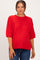 woman wearing a bright red short sleeve maternity sweater with a relaxed fit and ribbed details