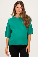 woman wearing a green short sleeve maternity sweater with a relaxed fit and visible baby bump