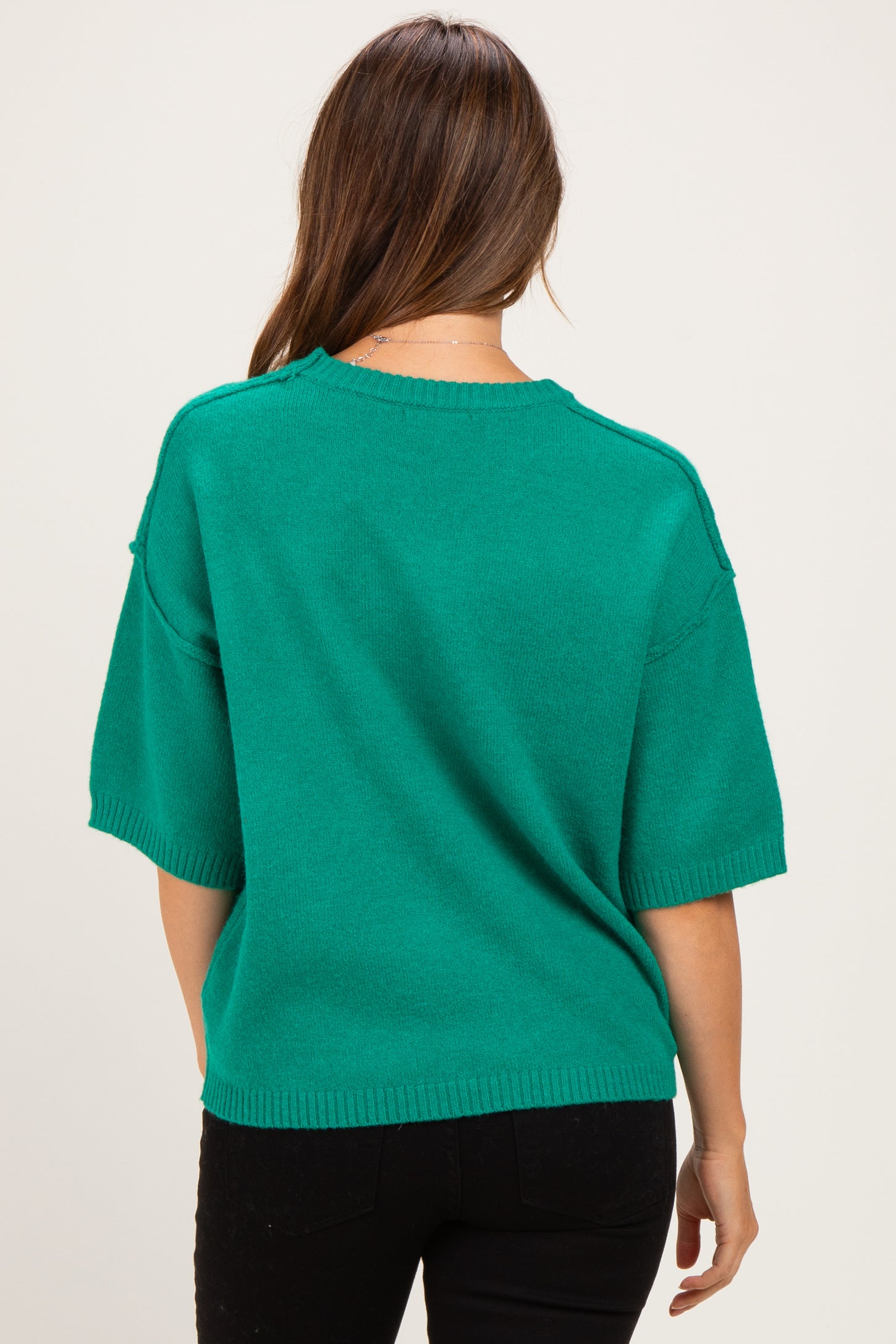 woman wearing a green short sleeve maternity sweater seen from the back