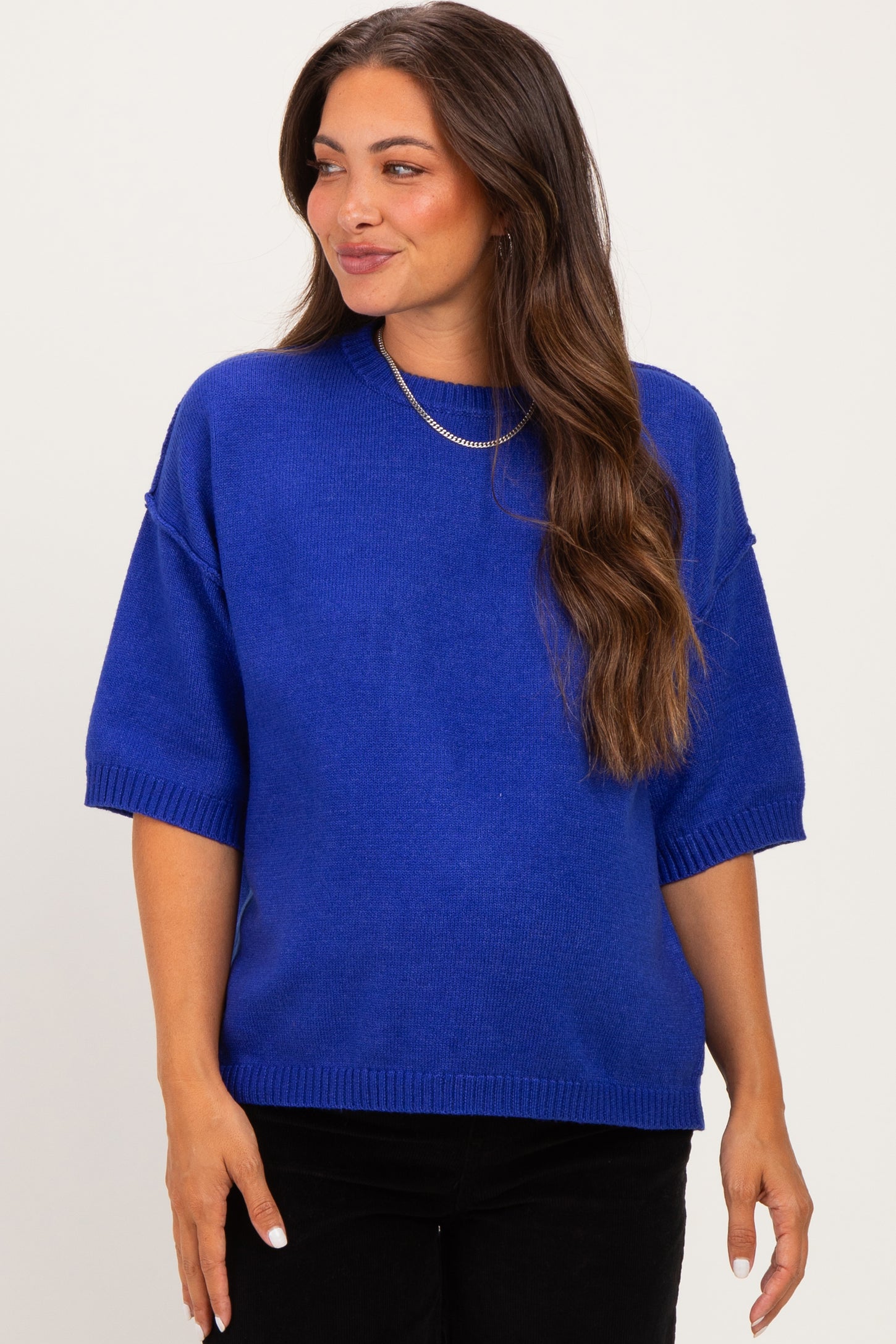 woman wearing a bright blue short sleeve maternity sweater with a relaxed fit and subtle ribbed detailing