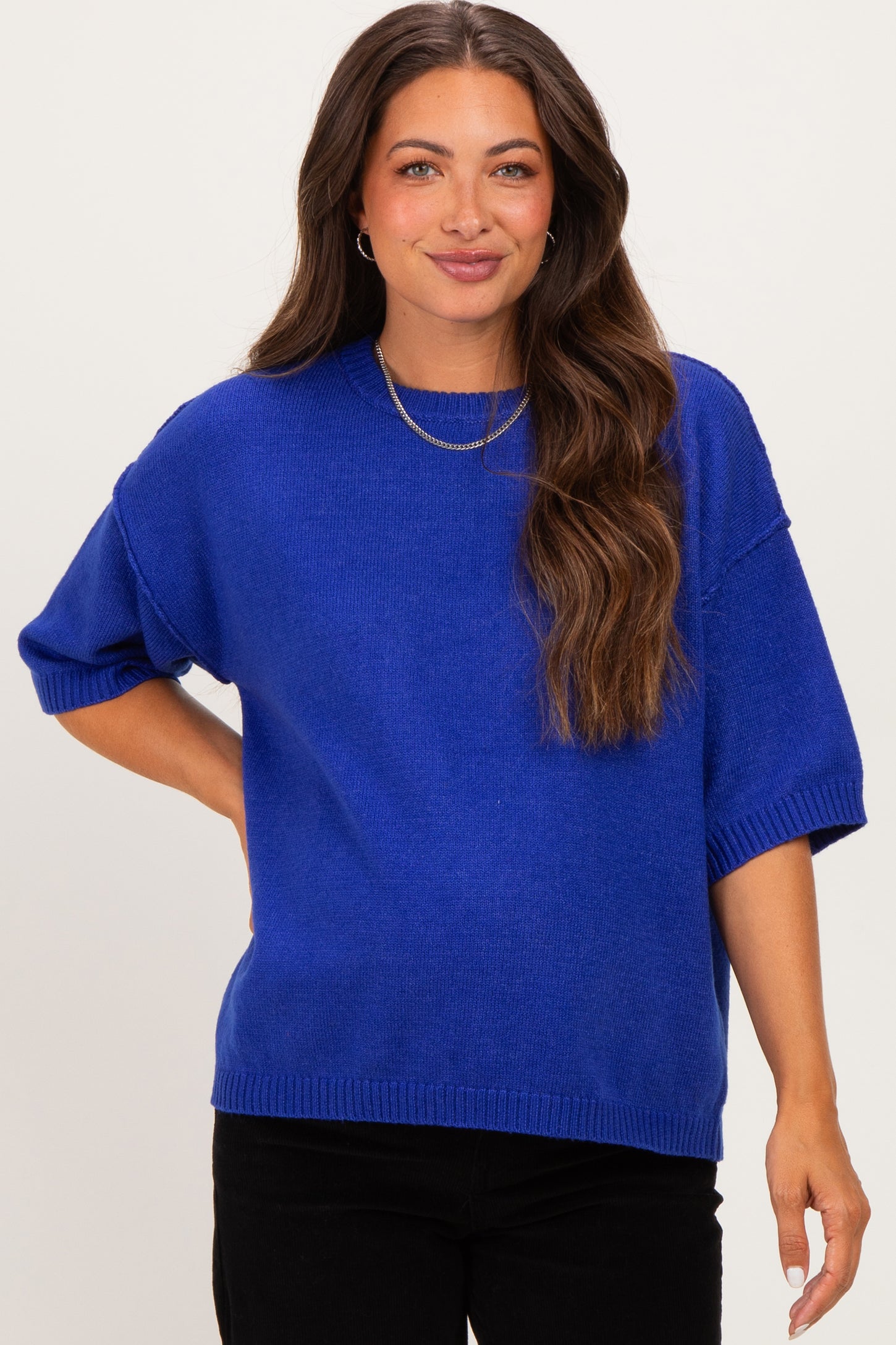 woman wearing a bright blue oversized maternity sweater with short sleeves and a relaxed fit