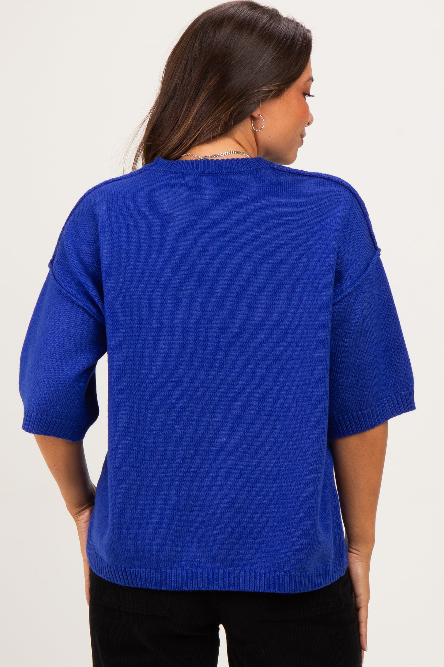 woman wearing a bright blue maternity sweater with wide sleeves, viewed from the back