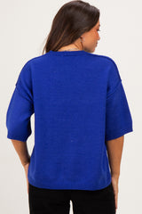 woman wearing a bright blue maternity sweater with wide sleeves, viewed from the back