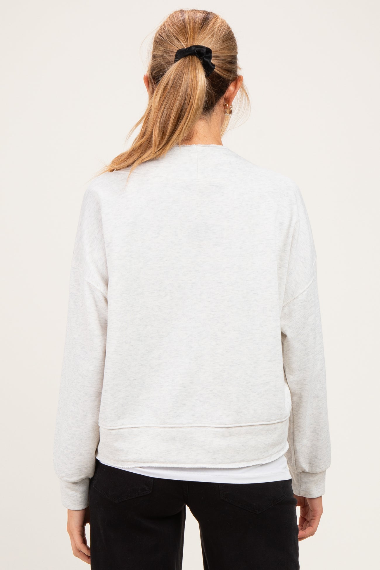 woman wearing a light gray maternity sweatshirt, shown from the back, with relaxed fit and drop shoulders