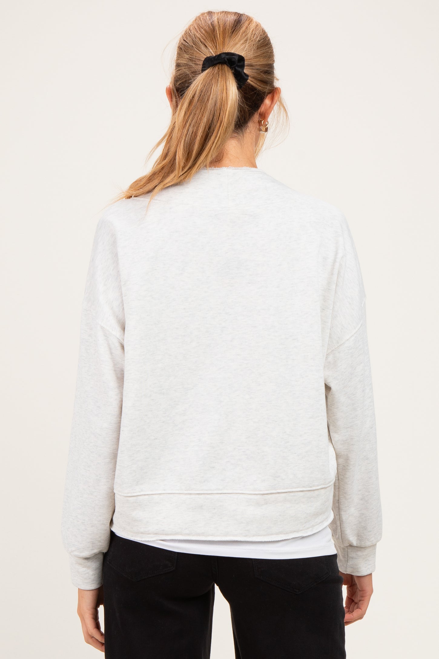 woman wearing a light gray maternity sweatshirt, shown from the back, with relaxed fit and drop shoulders