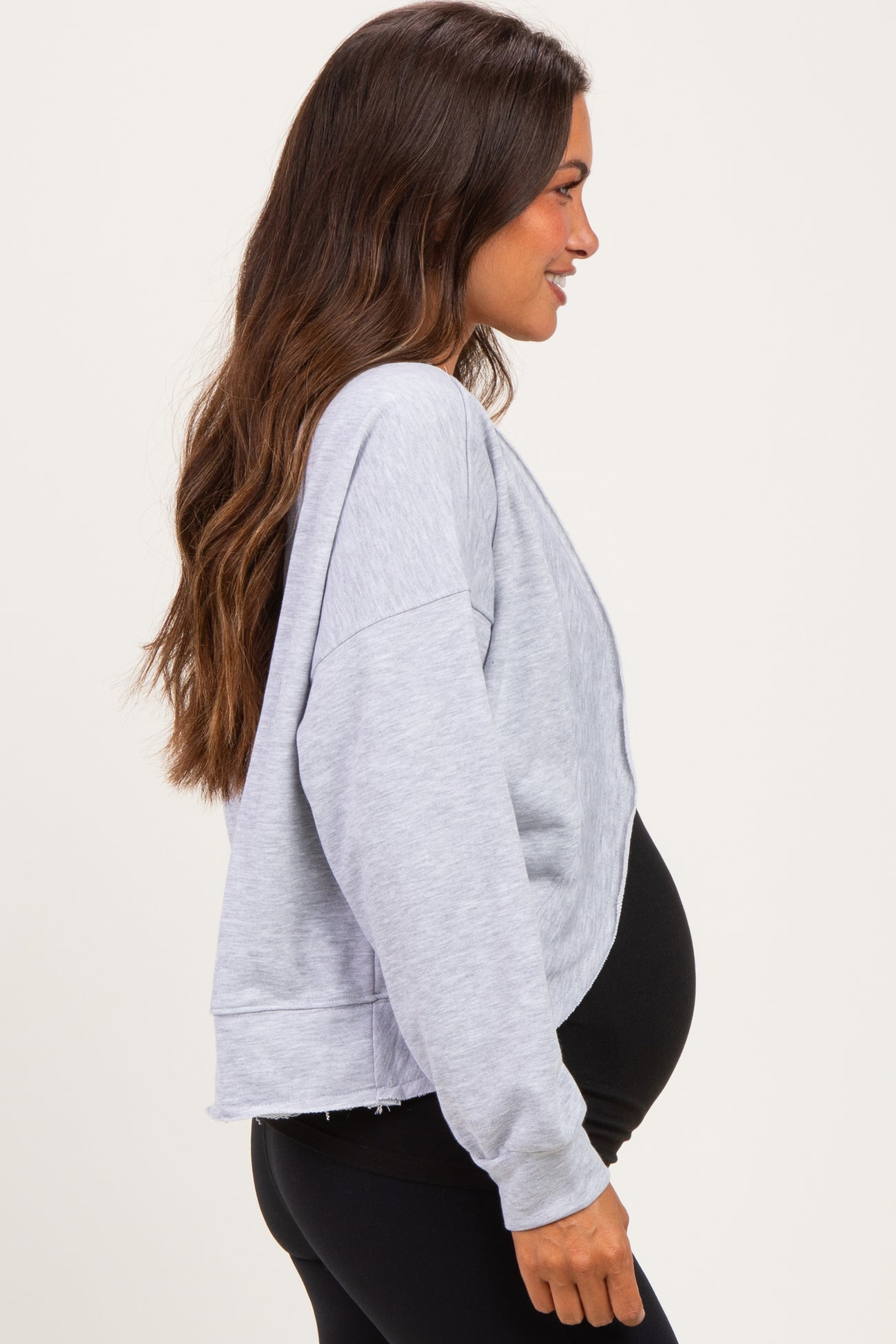 woman wearing a gray oversized maternity sweatshirt showing her baby bump