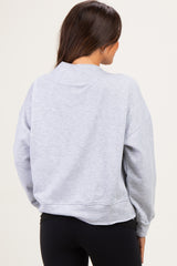 woman wearing a light grey maternity sweatshirt from the back, styled with black leggings
