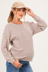 woman wearing a striped brown and cream maternity sweatshirt and cap, showing her baby bump