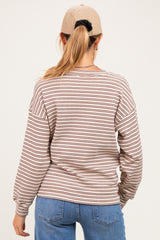 woman wearing a cream and rust striped maternity top with long sleeves, viewed from the back