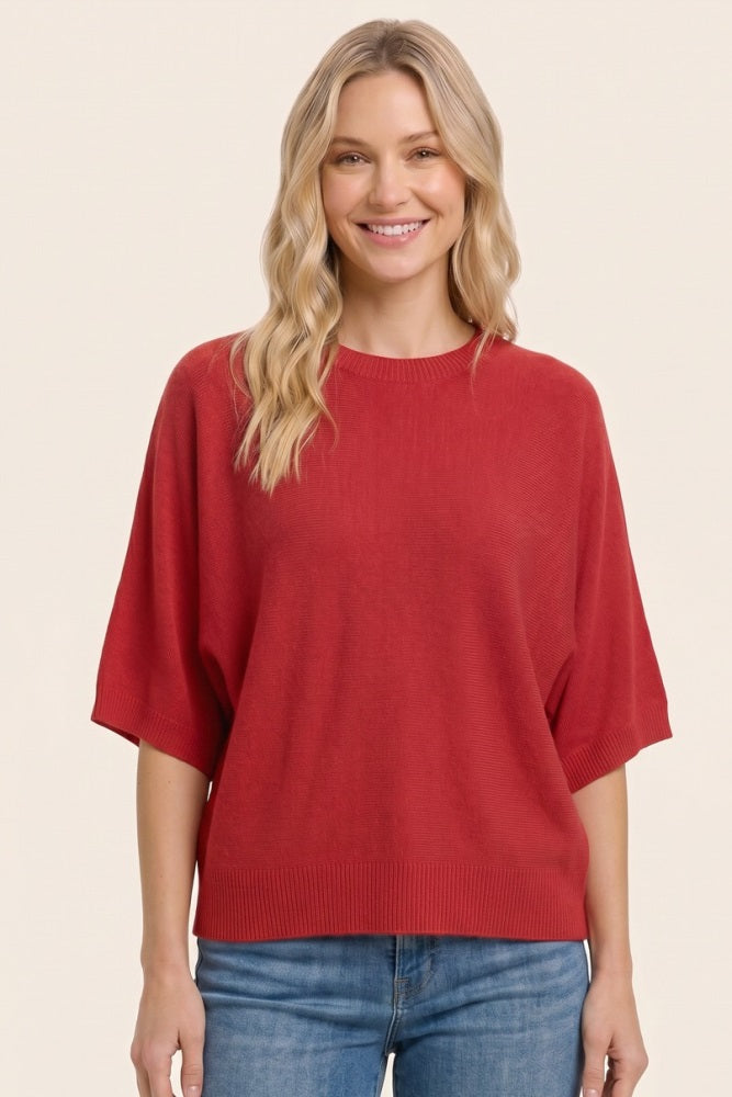woman wearing a red oversized short sleeve sweater with a relaxed fit and smiling