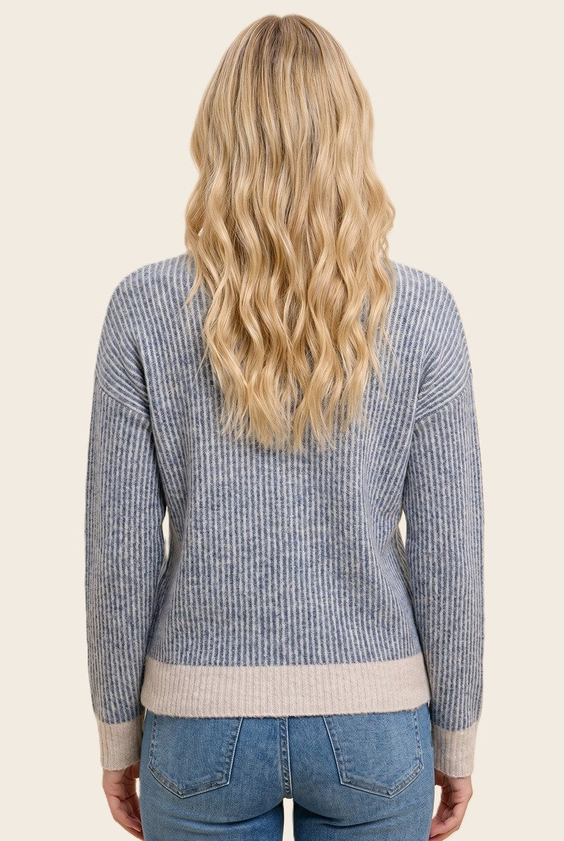 woman wearing a blue and gray striped sweater with a relaxed fit, view from the back, paired with light denim jeans