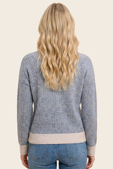 woman wearing a blue and gray striped sweater with a relaxed fit, view from the back, paired with light denim jeans