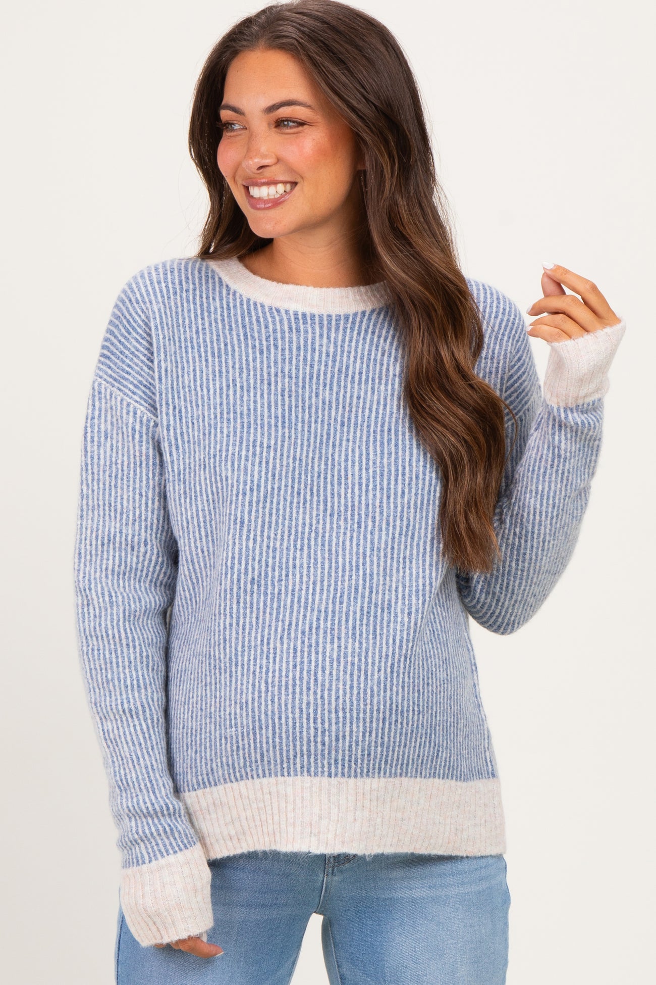 woman wearing a striped blue and cream maternity sweater with long sleeves and smiling