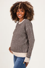 woman wearing a striped brown and cream maternity sweater and showcasing her baby bump