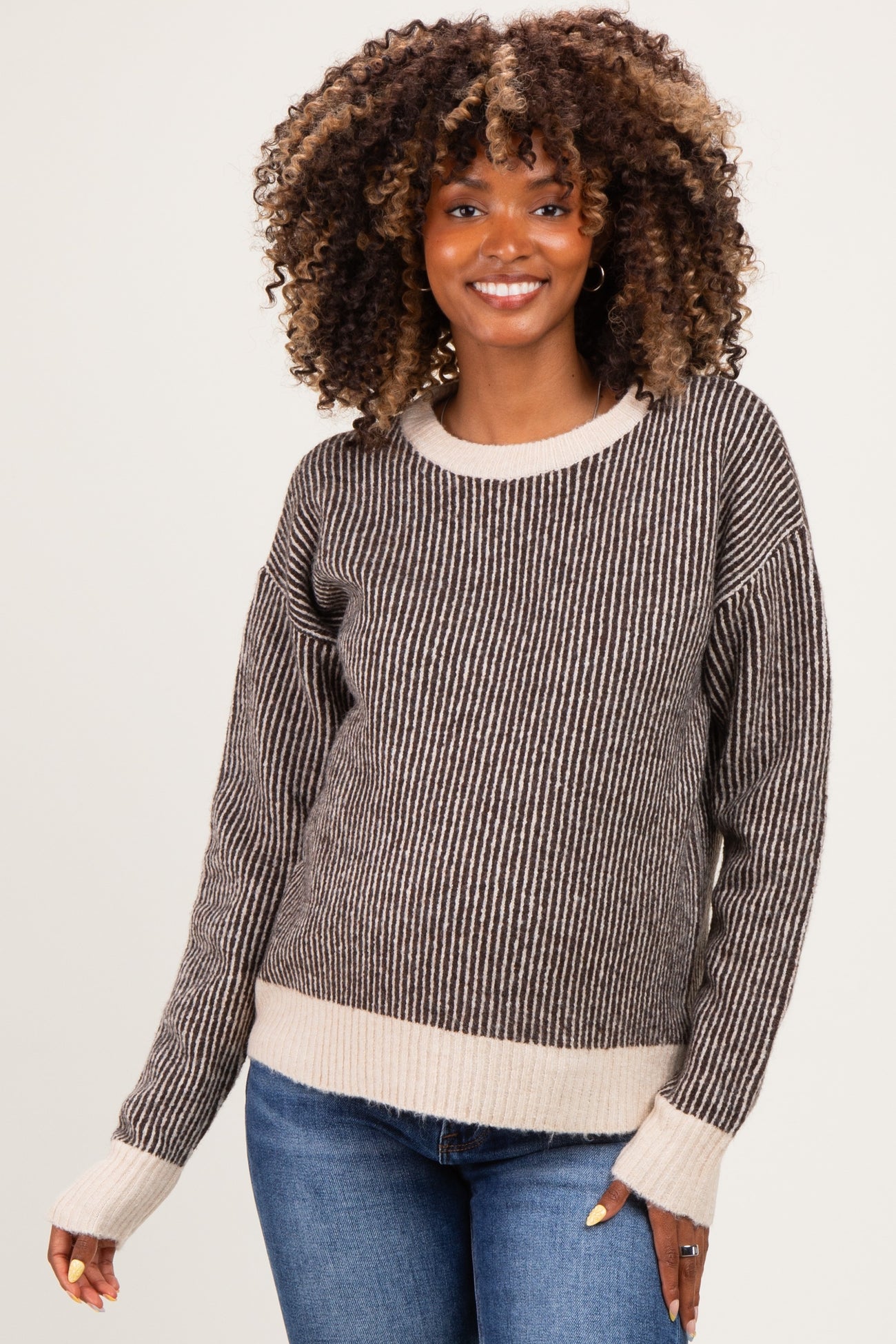 woman wearing a brown and cream striped maternity sweater with a relaxed fit and long sleeves