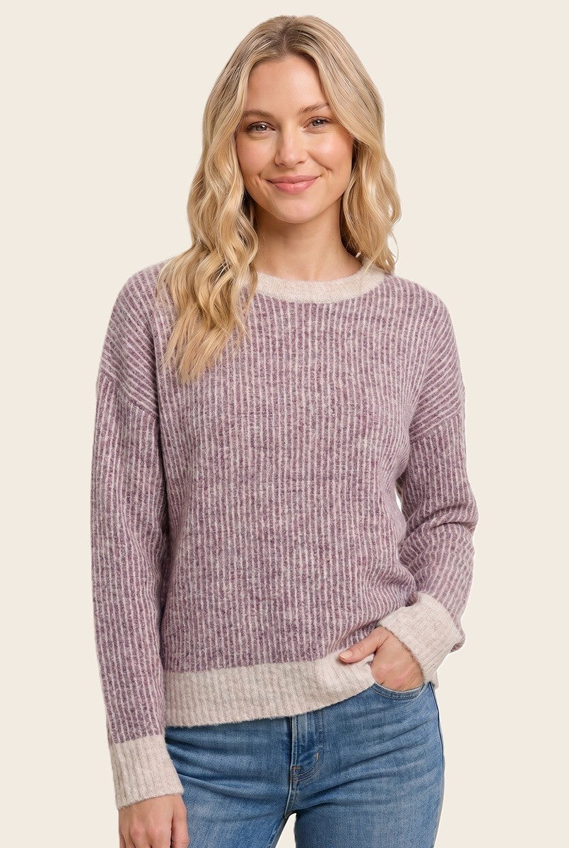 woman wearing a striped light purple and beige long sleeve sweater with a relaxed fit and ribbed hem