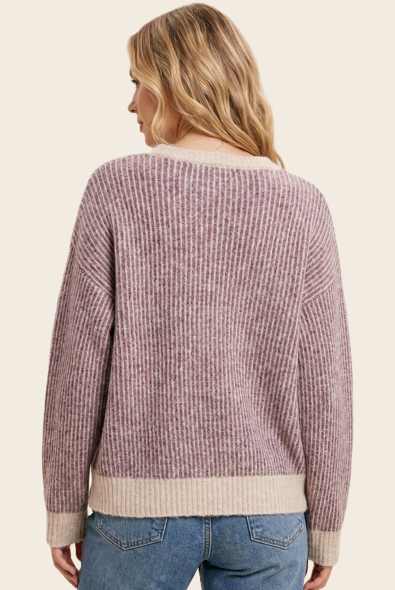 woman wearing a ribbed lavender and cream oversized sweater, viewed from the back, with light blue jeans