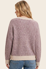 woman wearing a ribbed lavender and cream oversized sweater, viewed from the back, with light blue jeans
