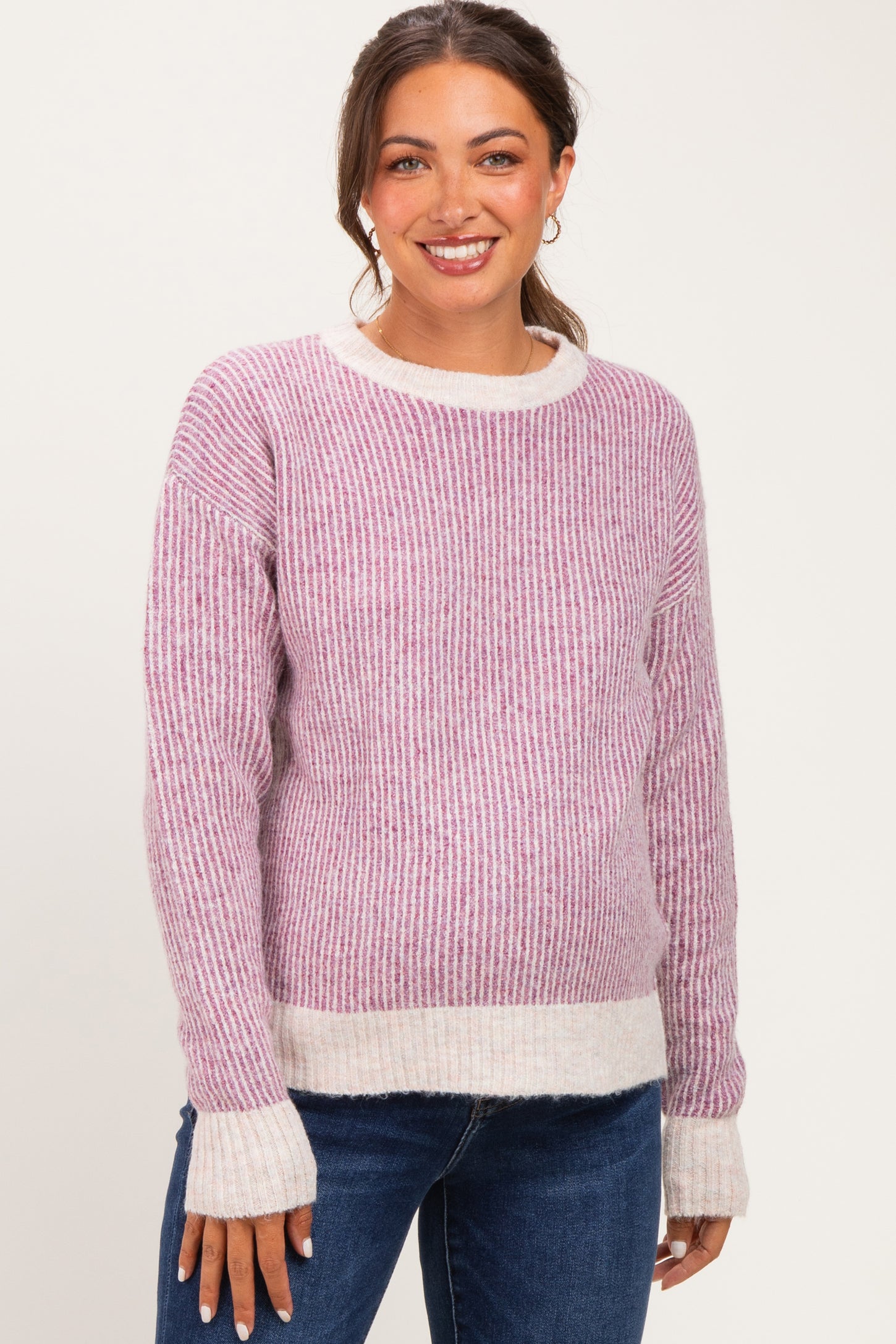 woman wearing a pink and white striped maternity sweater with a rounded neckline and long sleeves, smiling at the camera