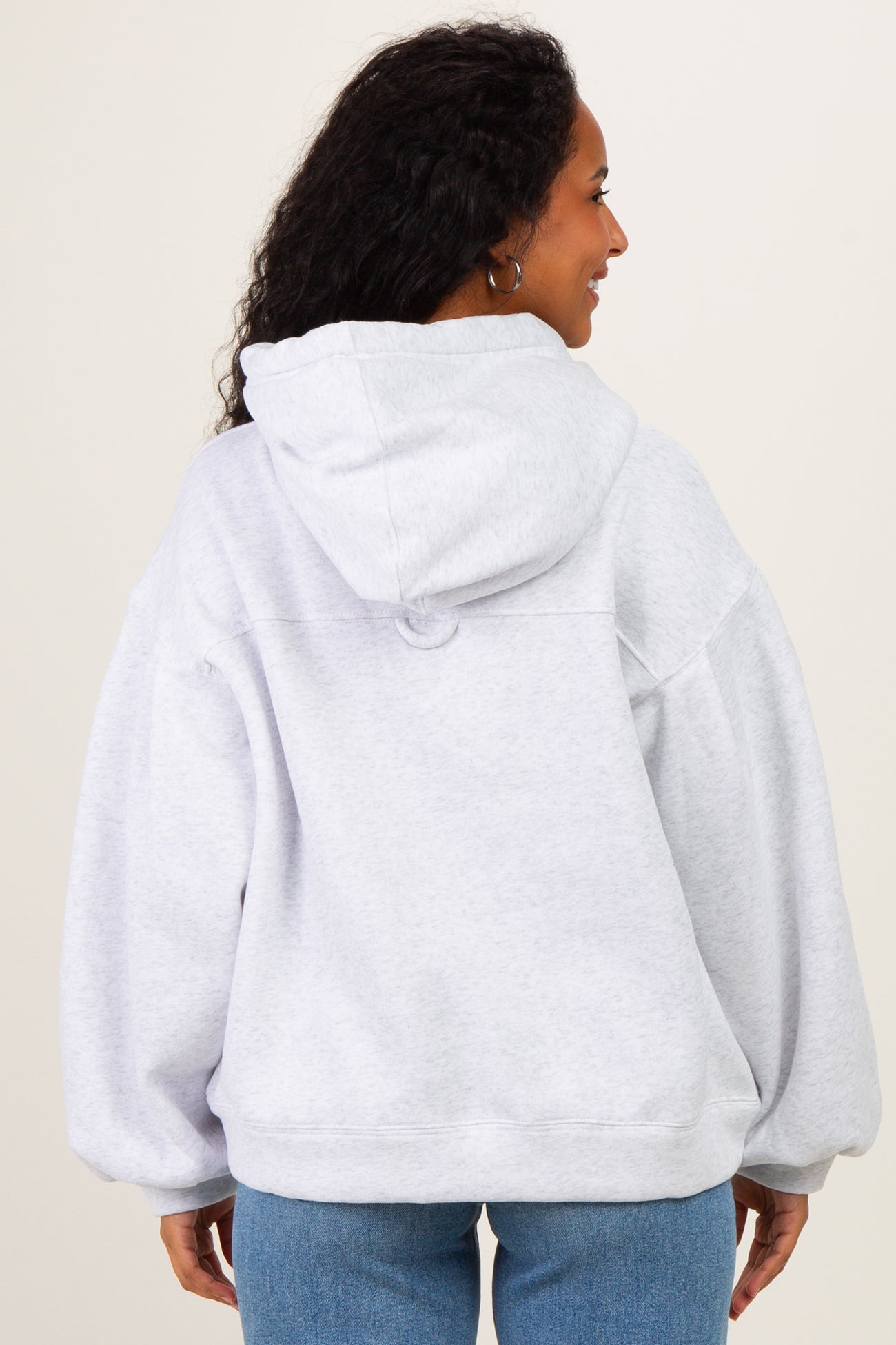 woman wearing a gray oversized maternity hoodie with a hood, seen from the back