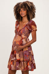 woman wearing a colorful floral maternity dress with puff sleeves and holding her baby bump