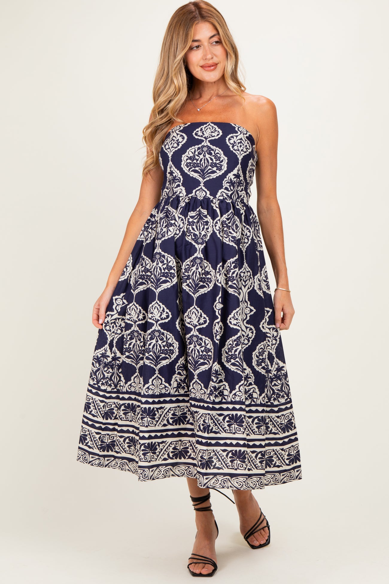 woman wearing a navy blue strapless maxi maternity dress with white floral patterns and a flowy skirt
